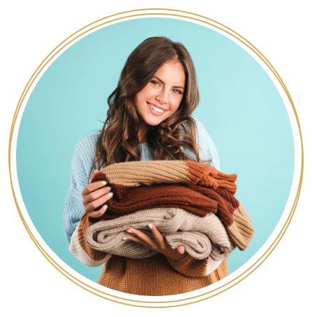 Vrolijke vrouw met een grote stapel fris gewassen handdoeken in diverse aardetinten