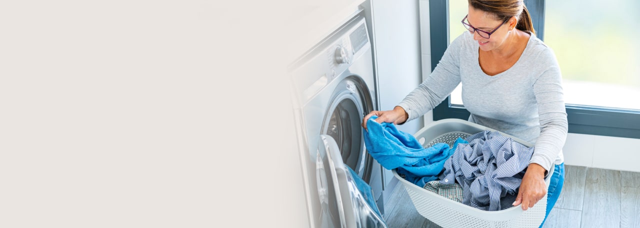 Vrouw doseert Wasgeurtje wasparfum in de wasmachine voor fris en geurig wasgoed.